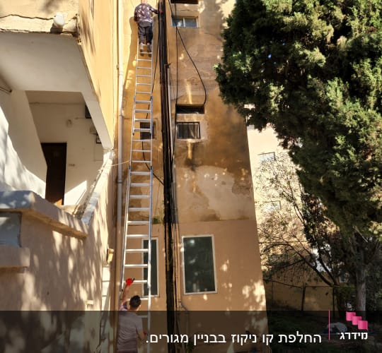 אדם על סולם ליד צינורות בניין